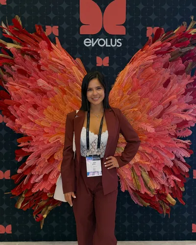 Fiorella at an Evolus event in front of a red and pink wings artwork