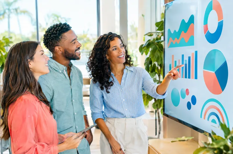 Team reviewing a colorful business dashboard on a wall screen